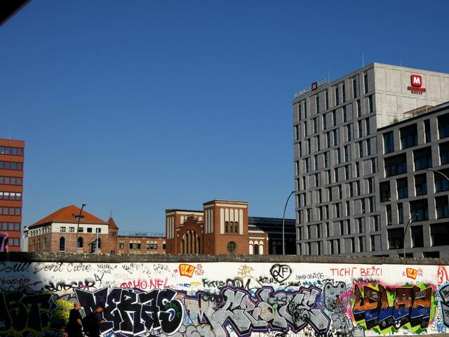 Nochmal ein Mauerstück mit dem Postbahnhof im Hintergrund. Rechts daneben ein weiterer neuer Hotelkomplex, das Meininger. Der Ostbahnhof mit guten Einkaufsmöglichkeiten liegt in unmittelbarer Nähe.