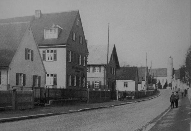Aus dem Jahr 1954 und damit wenige Jahre später und etwas weiter südlich stammt dieses Bild der Straße. Das einzige heute noch vorhandene Haus ist das dritte von links, nämlich das heutige Gebäude der früheren „adrett-Reinigung“. Die Häuser dahinter sind einem Geschäftshaus gewichen, die Häuser davor der jetzigen „Potenzialfläche“ („=Loch“). 
Das Bild stammt aus dem Buch „Gersthofen – Werden und Wachsen eines Gemeinwesens“ (1954).