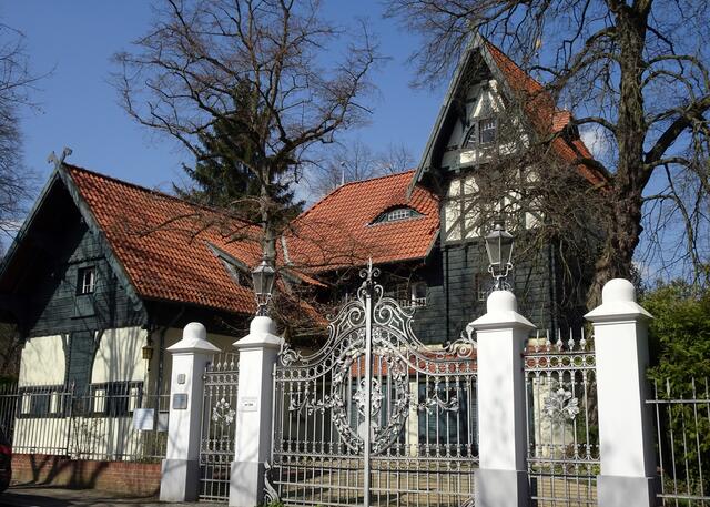 Das zweigeschossige Stallgebäude mit Kutscherwohnung auf dem Eckgrundstück Colomierstr. 2, Ecke Straße am Großen Wannsee, gehört zur Villa Langenscheiidt, recht aufwendig für ein Nebengebäude. Das schmiedeeiserne Einfahrtstor mit bemerkenswertem Blattwerkdekor fällt ins Auge. Hier führte einst ein breiter Fahrweg durch den Garten zur Villa.