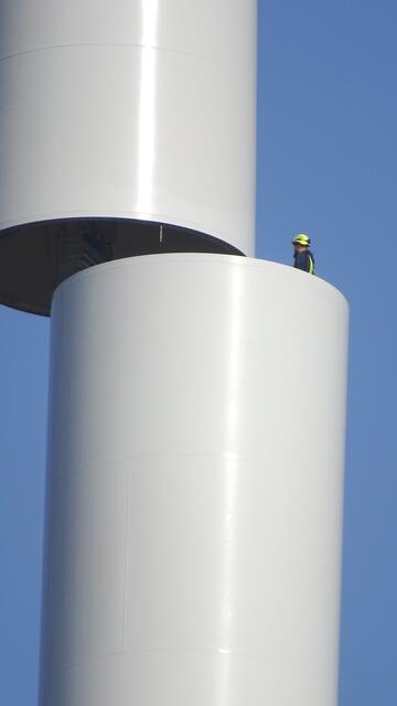 In luftiger Höhe bereitet ein Monteur die „Hochzeit“ des letzten Teilstücks des Turms vor ...