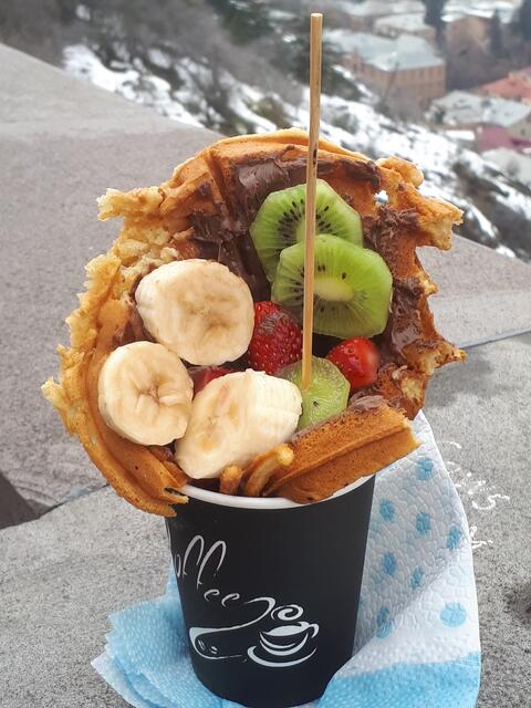 Bubble Waffle mit Obst und Nutella, serviert im Kaffeebecher. Gegessen in Tiflis zwischen Seilbahn und Mutter Georgiens.