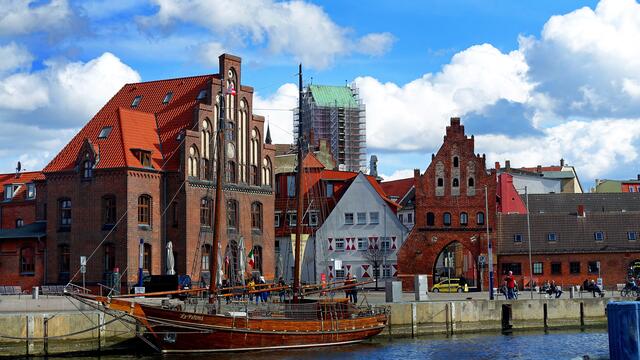 Am Alten Hafen ist der eingerüstete Nikolaikirchturm zwischen dem ehemaligen Zollhaus mit dem Staffelgiebel und dem kleineren historischen Wassertor zu sehen. Foto: Helmut Kuzina