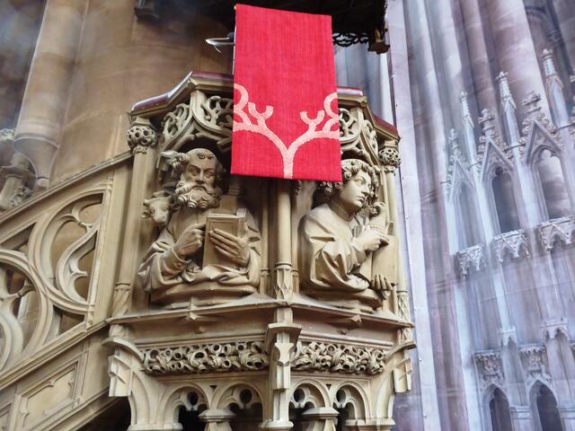 Die Brüstung zeigt die vier Evangelisten mit der Bibel und mit ihren Symbolen. Links ist Lukas mit dem Stierkalb zu sehen, rechts Johannes mit dem Adler.