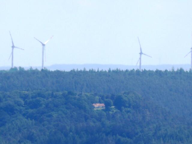 Im Wald oberhalb von Münchhausen ist die Waldgaststätte auf dem Christenberg zu erkennen. Dahinter stehen die Windräder von Emsdorf (Windpark Kirchhain).