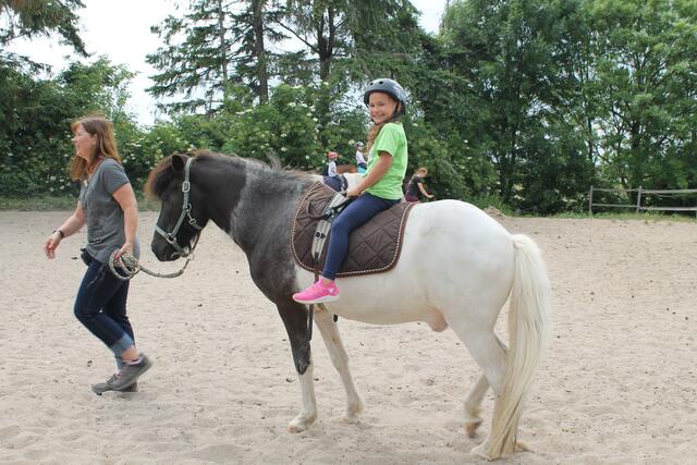 Anna, 7 Jahre, hat sichtlich Spaß auf dem Pony, das von Sylvia Grundmann geführt wird.