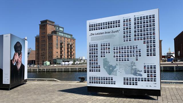 Die Info-Tafel nennt Namen und Orte der Fischer, die auf den Porträts der Ausstellung am Alten Hafen zu sehen sind. Foto: Helmut Kuzina
