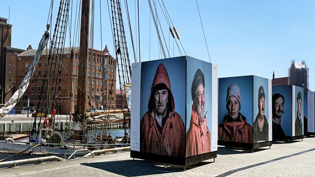Die Bilder von Jan Kuchenbecker und Franz Bischof stehen an der Kaikante des Alten Hafens. Die Ausstellung soll auf den schweren Berufsstand der Fischer aufmerksam machen. Foto: Helmut Kuzina