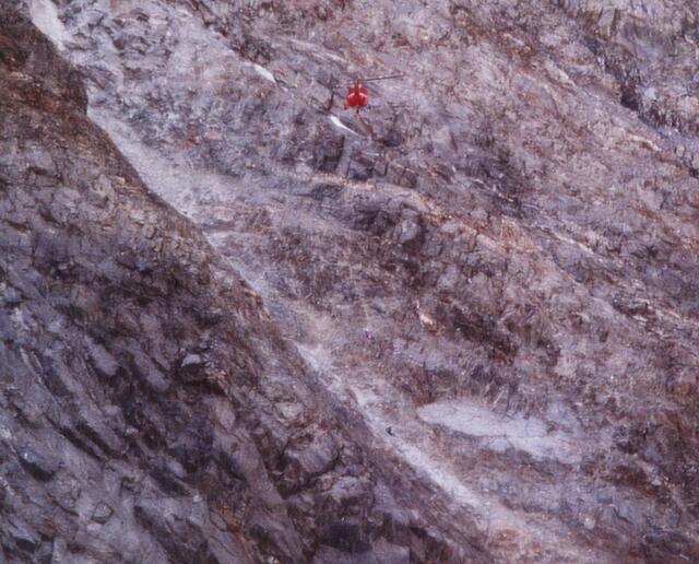 Oft kann auch Steinschlag tödlich enden. Der Leichnam eines von Felsbrocken getroffenen Bergsteigers wird aus einer Rinne geborgen. Ein Retter der Bergwacht seilt sich zu dem Toten ab. Trauriges Alltagsgeschäft für diese Männer.