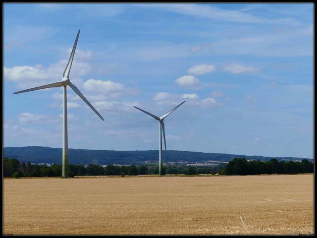 Windräder am abgemähten Feld und Deister im Hintergrund