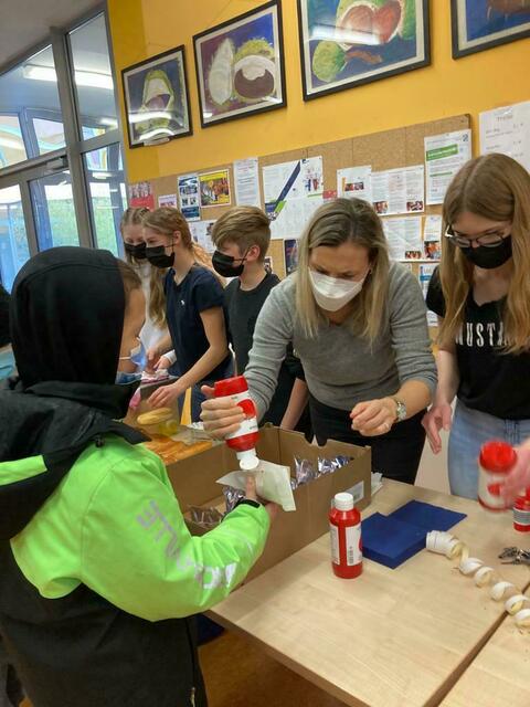 Lehrerin Sandra Eberhard-Remmele (weiße Maske) und ihre Schüler der 8dM organisierten eine Hot-Dog-Verkaufsaktion für die Kinderrechtsorganisation "Save the children".