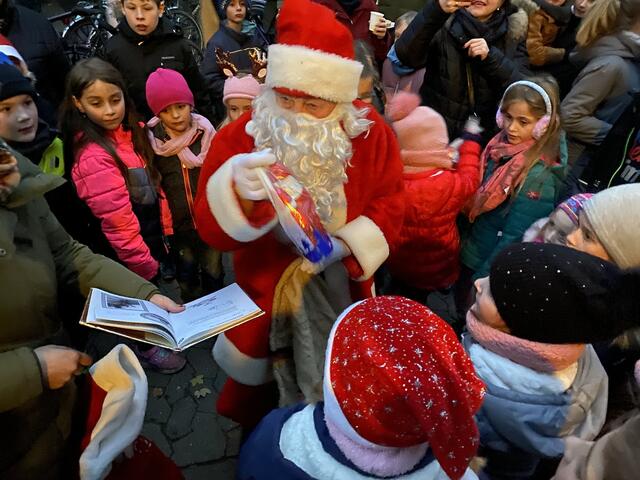 Nach Beantwortung der Fragen aus dem „Goldenen Buch“ bekommen die Kinder eine kleine Geschenktüte vom Weihnachtsmann überreicht.