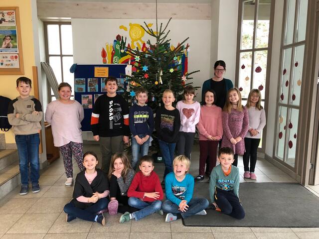 Die Klasse 3b mit ihrer Lehrerin Frau Mägele strahlt stellvertretend für die ganze Schule vor dem schön geschmückten Christbaum.