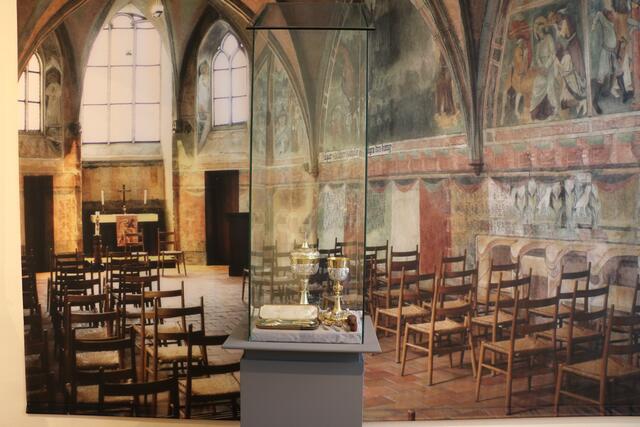Vitrine vor einem Bildhintergrund, auf dem die St.-Anna-Kirche in Augsburg abgebildet ist | Foto: Anna Pichlmaier