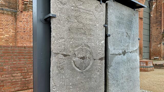 Die Grabplatte (links) für Hinrick und Dorthe Smoie (1560), Agneta Schmied (1624) und Joachim Burmester (1627) ist vielfältig gestaltet. Sie zeigt einen deutschen Reimvers aus dem Jahr 1560: „Ach, Gott, wie verzweifelt ist die Welt, die sich verlässt auf Güter und Geld und verlässt Gott den Herrn, der uns seine Güte und Barmherzigkeit zuwenden möge.“ Darunter findet sich ein Wappenschild bekrönt von einem Putto. Der Grabstein wird verziert von Eckmedaillons mit Evangelistensymbolen und einer vertieft eingehauenen gotischen Minuskel.
Die Grabplatte (rechts) für David Jochen Wulff und Ilsabe Capell entstand 1676 und wurde Mitte des 18. Jahrhunderts ergänzt. Die 300 mal 130 cm große Platte ist mit 2,5 Tonnen eine der schwersten erhaltenen Grabplatten der Marienkirche.