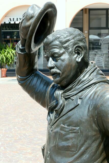 Gestatten Gino Cervi, besser bekannt als Bürgermeister Peppone, dem kommunistischen Gegenspieler von Don Camillo. Er lüftet seinen Hut zum Gruß an den schlagkräftigen Pfarrer gegenüber oder doch vor den Touristenscharen, die nur wegen des Filmduos in das verschlafene Brescello kommen?