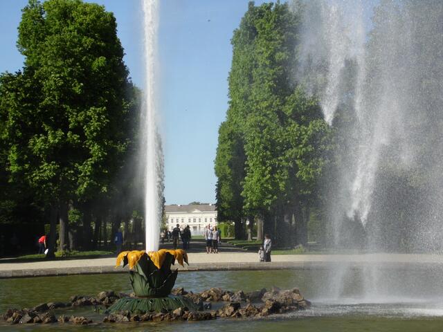 An heißen Sommertagen wird der Sprühregen zur Abkühlung genutzt. Im Hintergrund das Schloss.