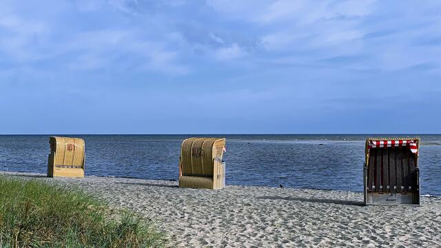 Ein paar Schleierwolken am lichtblauen Himmel, plätschernde Wellen der flachen Ostsee, viele Spuren im knirschenden Sand, fast extra dekorativ aufgestellte Strandkörbe und die weite Sicht bis zum Horizont sind hier nicht Details eines professionellen Werbefotos, sondern zeigen einfach das reale Landschaftsbild.