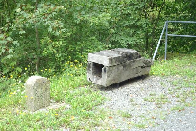 alter Grenzstein mit altem hölzernen Wasserrohr