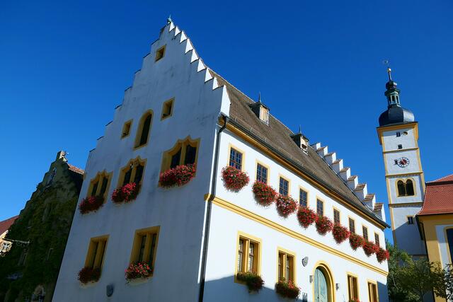 Das Ensemble aus Rathaus und evangelischer Pfarrkirche unter dem südlich blauen Himmel von Mainbernheim