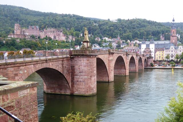 Vom nördlichen Ende der Alten Brücke (Karl-Theodor-Brücke) geht der Blick links hinauf zum Schloss. Rechts im Bild steht der Turm der Heiliggeistkirche. Oben links sind auf dem Königstuhl der Fernsehturm und ein etwas höherer Fernmeldeturm der Deutschen Telekom zu sehen.