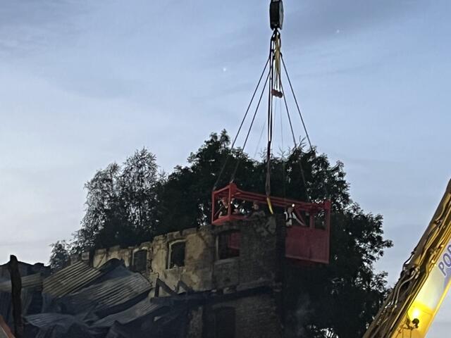 Händisches Abtragen einer Mauerwand mittels Arbeitsfläche über Kran