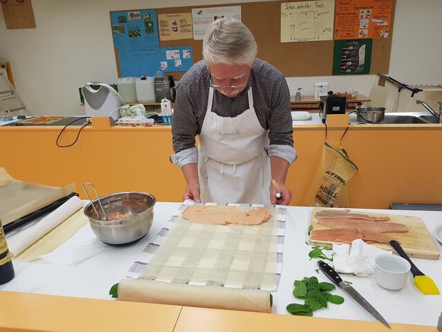 Georg Lipp hat hier bereits die Forellenfarce auf den Strudelteig gestrichen, jetzt noch die Filets und die Spinatblätter drauf, zusammenrollen, dann ist das Meiste schon geschafft.