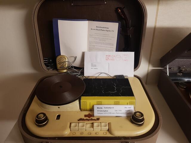 Dieses Selectophon T5 Bj. 1957 von Nora war einmal ein technisches Wunderwerk. Was ausschaut wie ein Buch mit einem gelben Buchrücken ist die Tonbandkassette. Dieses Gerät wurde dem radio- und Telefonmuseum Wertingen von Günter Jakob aus Augsburg gespendet.
Abmessungen (BHT) 460 x 190 x 350 mm  - Vielspur; 8,5/11,5/20 cm/s.; 35-mm-Endlosband in Spezial-Kassette. Spurauswahl durch Zählwerk und Wahlschalter. 3-Touren-Plattenspieler eingebaut, Überspielung von Platte auf Band möglich. Cassette (book shape, tape 35mm wide). Speeds: 20 cm/s; 11,5 cm/s; 8,5cm/s.  - Nettogewicht: 13.5 kg  - Originalpreis:  768.00 DM.
