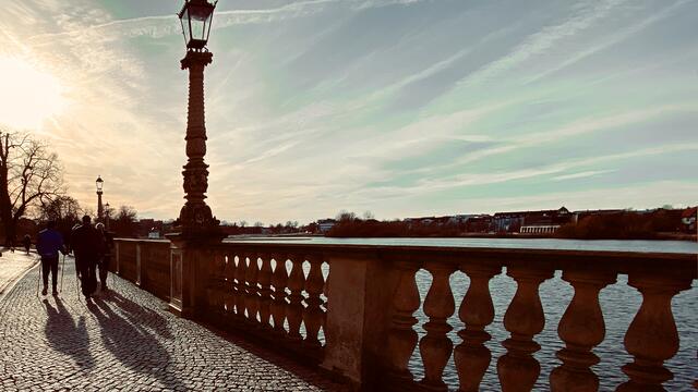 Lange Schatten erzeugen die Spaziergänger auf der Schweriner Schlossinsel. Foto: Helmut Kuzina