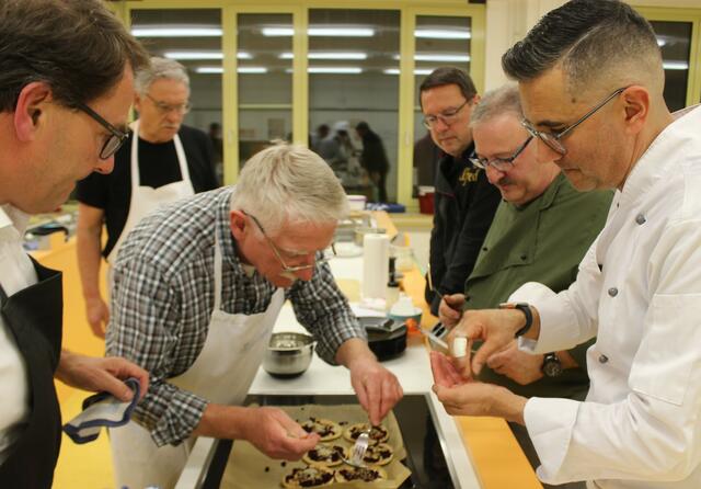 Georg Lipp verteilt noch etwas Fleur de Sel mit der Gabel auf die fertigen Flammkuchen und  Claudio Ebner streut noch die gehackten Walnüsse darauf. Während die anderen genau zuschauen, ob das alles so paßt.