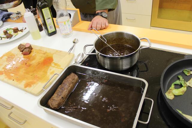 Vorne liegt noch ein Rehrückenfilet im asiatischen Sud, im Topf dahinter die Wildsauce und in der Pfanne der geröstete Pak Choi. 