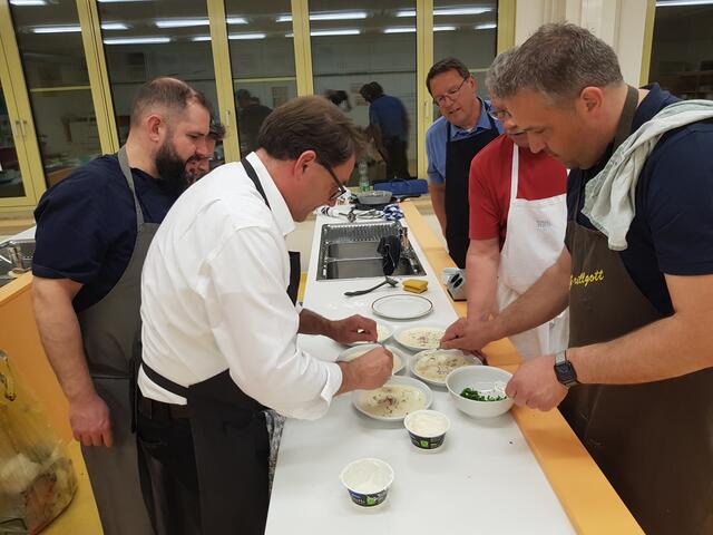 Die Suppe wird angerichtet. Ein kleines Ricottanockerl kommt in die heiße Suppe. Stefan Kaiser (rechts) streut noch feine Schnittlauchröllchen und verschönert die delikate Suppe noch mit feinen Radieschen Juliens als Garnitur.