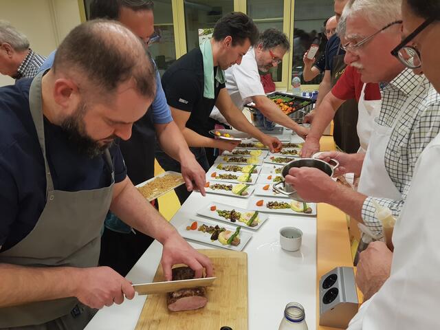 Johannes Steichele tranchiert das den auf den Punkt gegarten Kalbsrücken, während die anderen Köche bereits alle Hände voll zu tun haben mit Anrichten.
