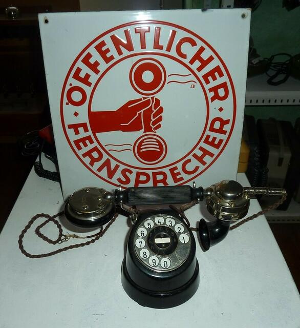 Das alte Emailleschild war früher an den Ämtern angebracht, wo es öffentliche Fernseprecher gab. Dieses Telefon war aber dort nicht in Gebrauch. Das "Kuhfuß"-Telefon, gebaut ab 1925 bis ca. 1935 ist hier mit einem bayerischen Telefonhörer ausgestatet.
