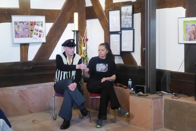 Freddy Albers greift zum Mikrofon, um das nächste Elvis-Lied zur Ausstellungseröffnung am 05.05.2024 zu singen. Neben ihm, der aus Hallenberg stammt und mit bürgerlichem Namen Carsten Hesse heißt, sitzt seine Frau Marion Klabes-Hesse.