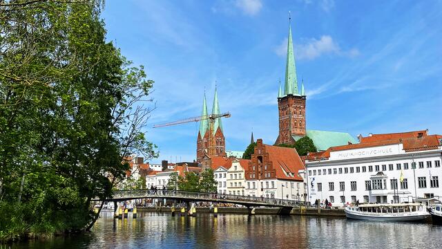 Von der Uferpromenade an der Trave bietet sich die Sicht auf die Doppelturmanlage von St. Marien und den Aussichtsturm der Petrikirche. Die „Professorenbrücke“ führt hinüber zur Musikhochschule. Foto: Helmut Kuzina
