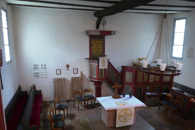 Blick von der Empore zum Altarraum. Mittig über den Kindergrabsteinen links von der Kanzel ist das Hugenottenkreuz angebracht.