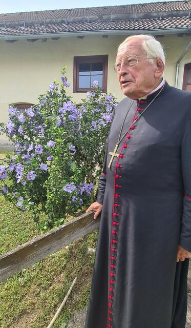 Bischof emer. Dr. Walter Mixa am Hibiskus-Strauch vor dem Pfarrstadel Merazhofen