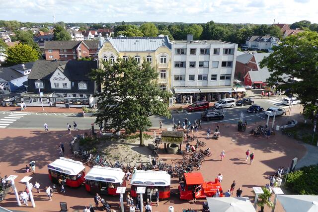 Die rote Dünenbahn transportiert die Urlauber zwischen Duhnen und Sahlenburg. Hier hält sie am Dorfbrunnen, dem Wahrzeichen des Stadtteils Duhnen.