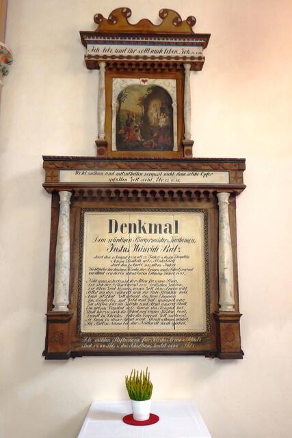 Im Bereich des Eingangsportal wird weiteren Gönnern gedacht. Der Kirche, den Armen und der Schule stifteten sie 2400 Thaler. Die Kosten für das von ihnen erbaute Schulhaus sollen 1600 Thaler betragen haben. „Denkmal / Dem würdigen Bürgermeister &amp; Kirchensen: / Justus Heinrich Balz / starb den 1. August 1820, alt 72 Jahre &amp; dessen Ehegattin / Anna Elisabeth gebr. Finkeldey / starb den 11. April 1815, alt 64 Jahre / Wohlthäter der hiesigen Kirche, der Armen und Schuljugend / gewidtmet von deren dankbaren Erben im Jahr 1821. …“