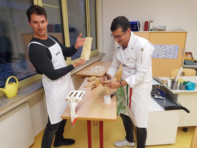 Martin Klaus präsentiert hier stolz seinen gelungenen Nudelteig. Claudio Erdner unterstützt ihn beim Herstellen der Teigplatten für die Schluzkrapfen.