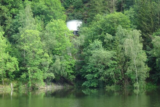 das runde Gebäude ist das Wasserschloss, es soll die - bei der Stromerzeugung (Turbinen - Generator)  - enstehende großen Kräfte bei der Abschaltung der Turbinen mindern und einen Wasserschlag zu verhindern