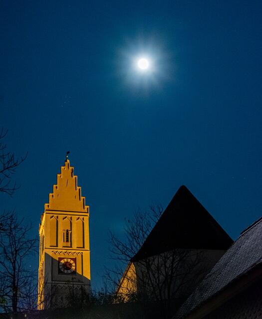 Neben dem Vollmond und zwischen Ästen Jupiter ist über dem Kirchturm der offene Sternhaufen Plejaden zu erkennen.