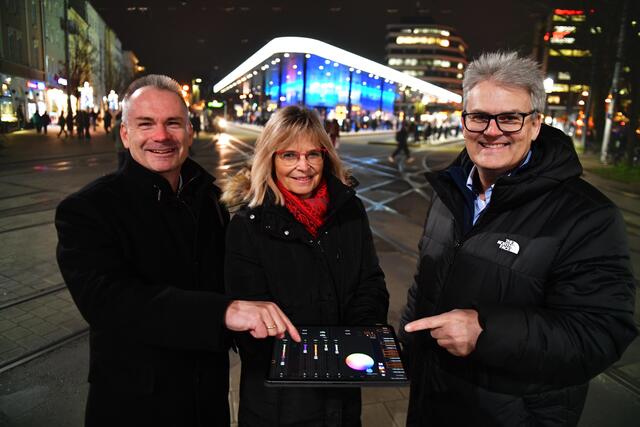 swa-Geschäftsführer Rainer Nauerz (v.re.), die Leiterin Fahrbetrieb, Stefanie Rohde, und der Leiter Fahrzeuge, Klaus Röder, haben die Fassadenbeleuchtung am Kö-Gebäude wieder eingeschaltet. | Foto: SWA/Thomas Hosemann