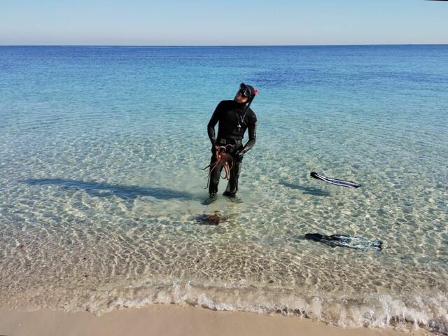  Ein privater Schnorchler ist stolz auf seine Beute (Tintenfische) und erklärt die Fangmethode. In einem, gerade noch handlichen, Betonstück waren Röhren eingearbeitet, in der sich die Tintenfische zur Ruhe/Schutz zurückgezogen hatten - bis der Flossenmmensch kam. 