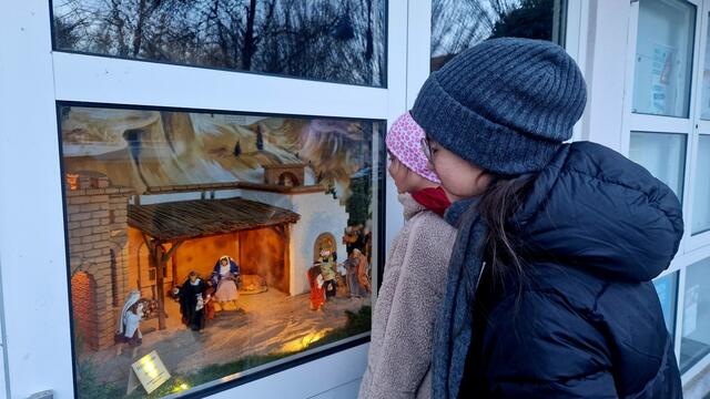 Mit viel Liebe zum Detail baut Archivar Wolfgang Bobinger alljährlich die Guckkastenkrippe hinter der Fensterscheibe des Rathauseingangs auf, hinter der eine traditionelle Krippenlandschaft mit Oberammergauer Figuren zu sehen ist. Beim „Krippenschauen“ auf der Rathaustreppe leuchten nicht nur Kinderaugen. | Foto: Stadt Bobingen