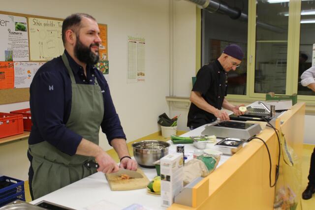 Johannes Steichele schneidet hier Gemüse während hinten Klaus Hill nochmal das Rezept studiert.