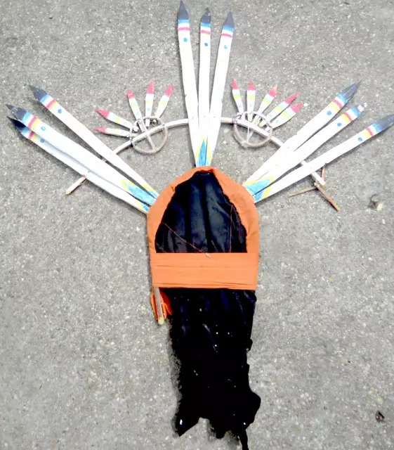 Die Männer der Mescalero-Apachen tanzen bei anhaltender Trockenheit nachts mit diesen Kopfaufsätzen an der Spitze der Bergkuppen. An der Spitze hölzerne Pfeile, die die Nachtwolken anritzen sollen. Dass man mit der glühend heißen Unnachgiebigkeit von Vater Sonne nicht zufrieden ist, und sich so anderen Göttern zuwendet, soll er ja nicht sehen.
Karl May hat statt diesem Holzgerüst bei Winnetous Stamm den Federputz der Sioux übernommen .
Kopfaufsatz und Fotoaus dem internationalen Maskenmuseum Diedorf