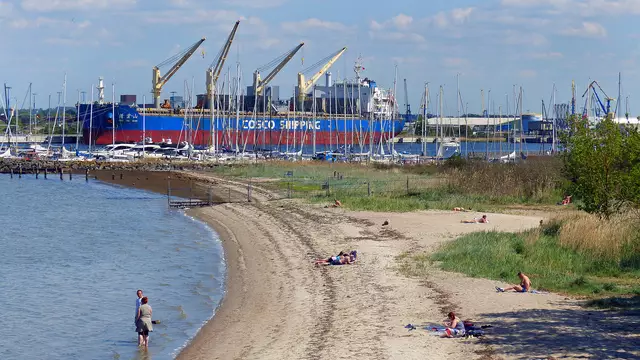 Strandurlauber halten sich am Badestrand auf, doch die Wassertemperatur liegt noch bei +11°. Foto: Helmut Kuzina