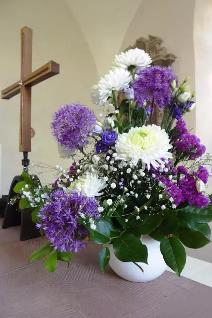 Aktueller Blumenschmuck auf dem 1958 von Horst Jaritz gefertigten Sandsteinaltar mit dem Altarkreuz, das ebenfalls 1958 nach einem Entwurf von Friedrich Bleibaum aus Marburg gestaltet wurde.