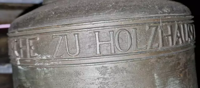 Die oberste Glocke aus dem Jahr 1947 trägt die Inschrift:
FÜR DIE EV. KIRCHE ZU HOLZHAUSEN /EDER
VON GEBR. RINCKER IN SINN 6280

               METALL GESTIFTET VON
             KARL THIELMANN HAIGER